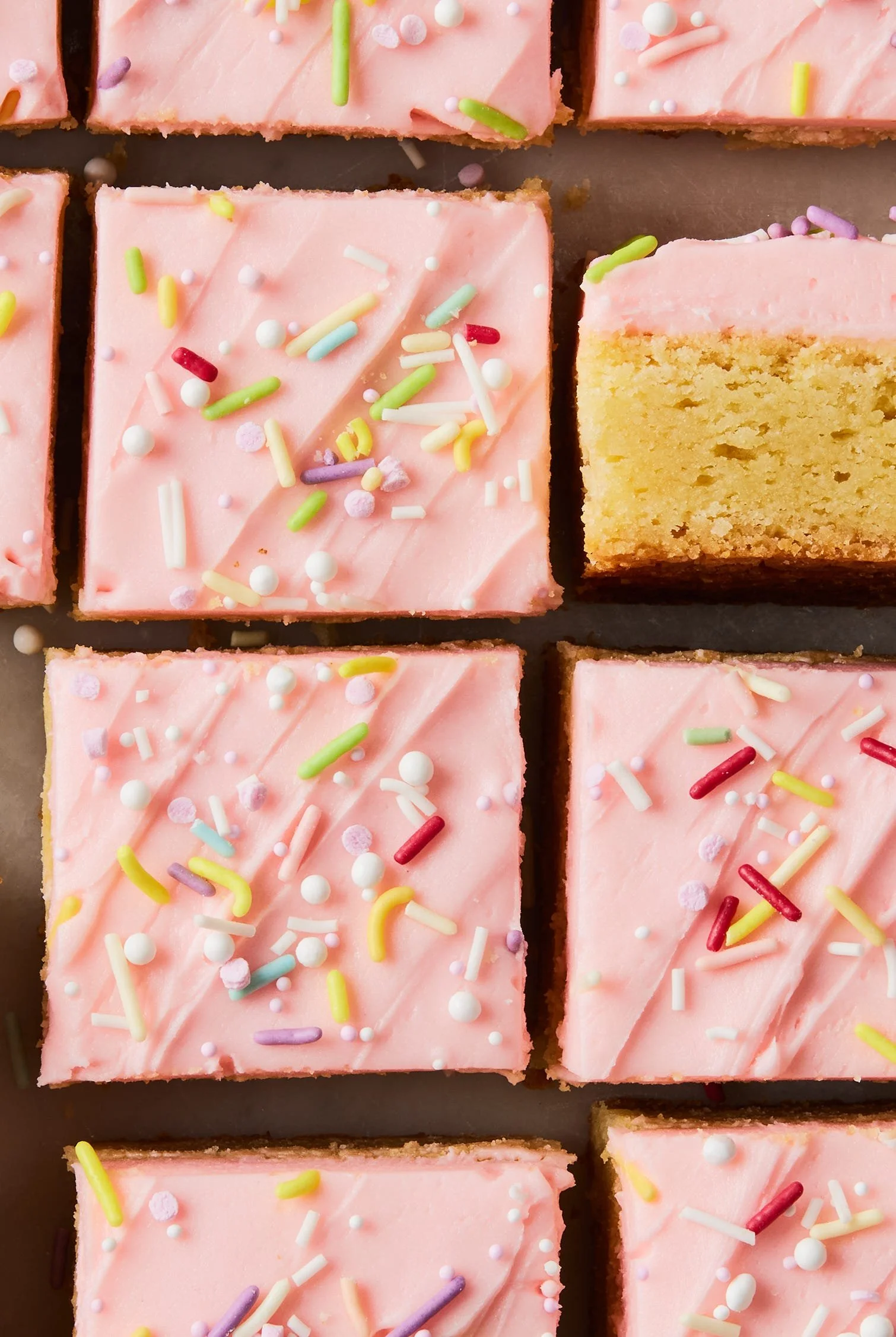 Chewy sugar cookie bars topped with colorful sprinkles and a glass of milk.