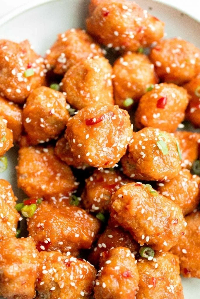Plate of Sweet Chili Chicken Bites garnished with peppers and herbs