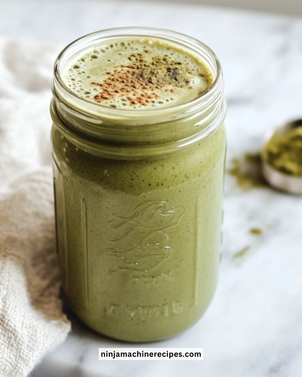 Banana Matcha Smoothie in a glass with banana slices and matcha powder