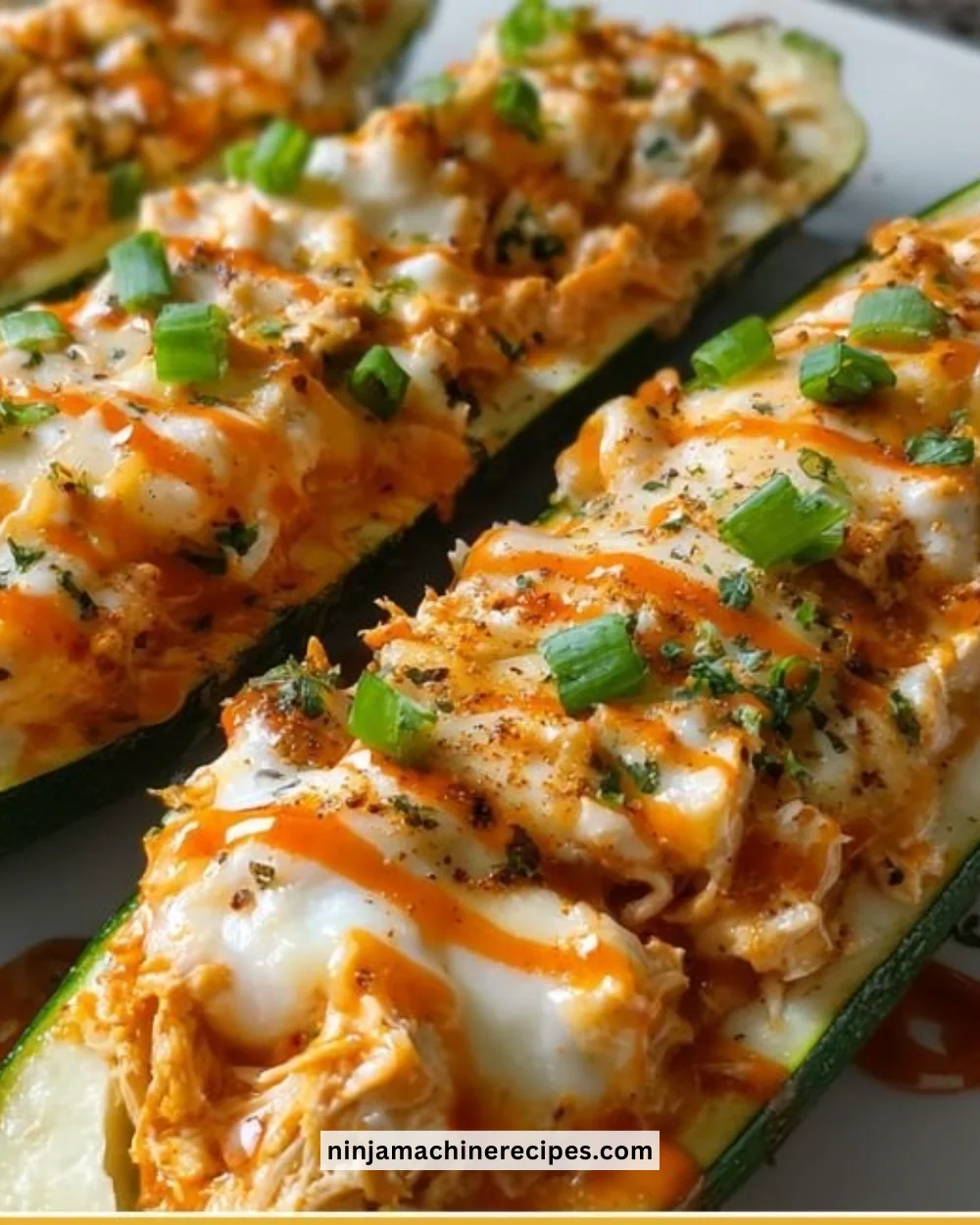 Buffalo Chicken Zucchini Boats topped with cheese and spicy sauce
