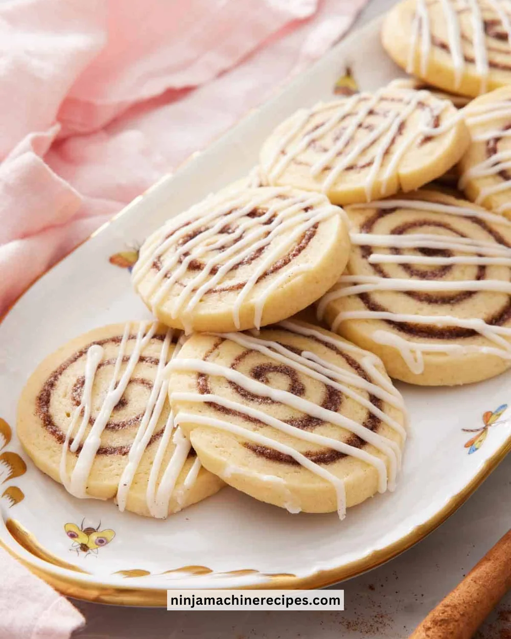 Freshly baked cinnamon roll cookies topped with icing on a cooling rack.