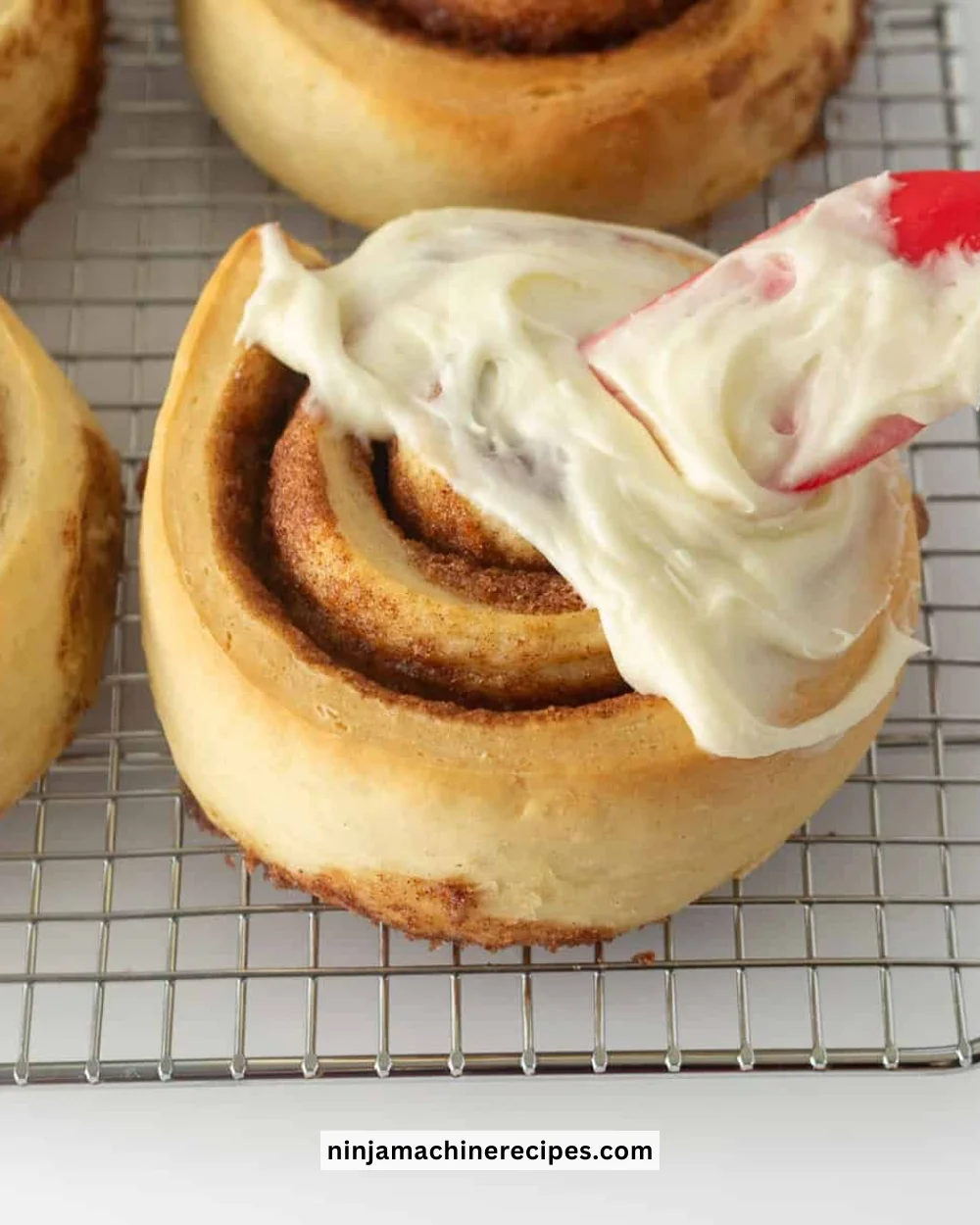 Cream cheese frosting drizzled over freshly baked cinnamon rolls