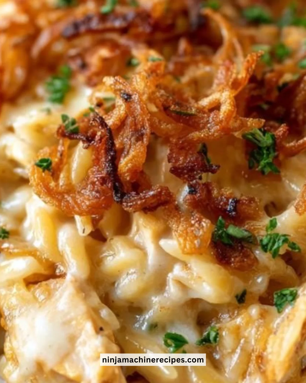 French onion chicken orzo casserole topped with melted cheese and garnished with herbs.