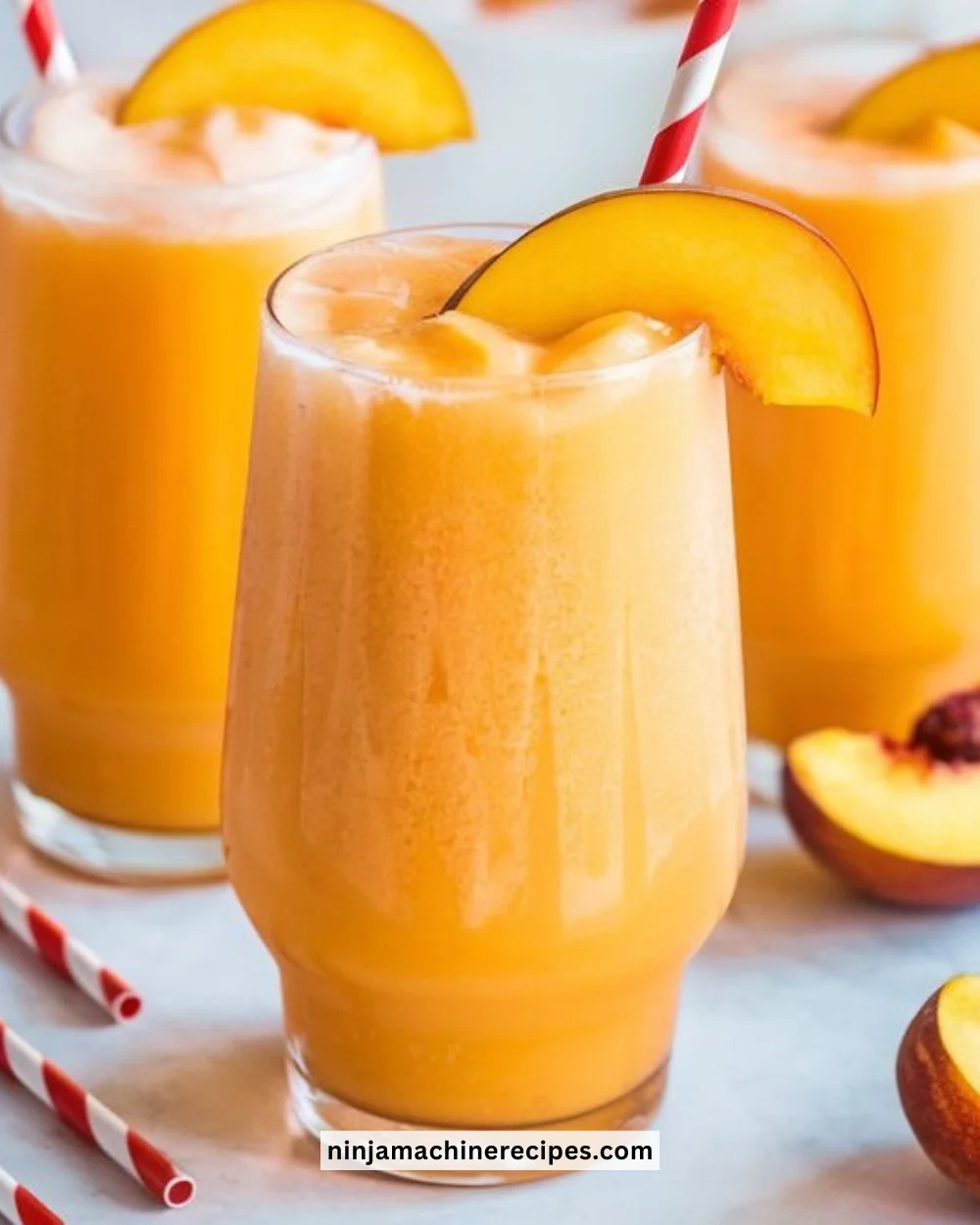 Homemade peach slurpees in a glass with fresh peaches
