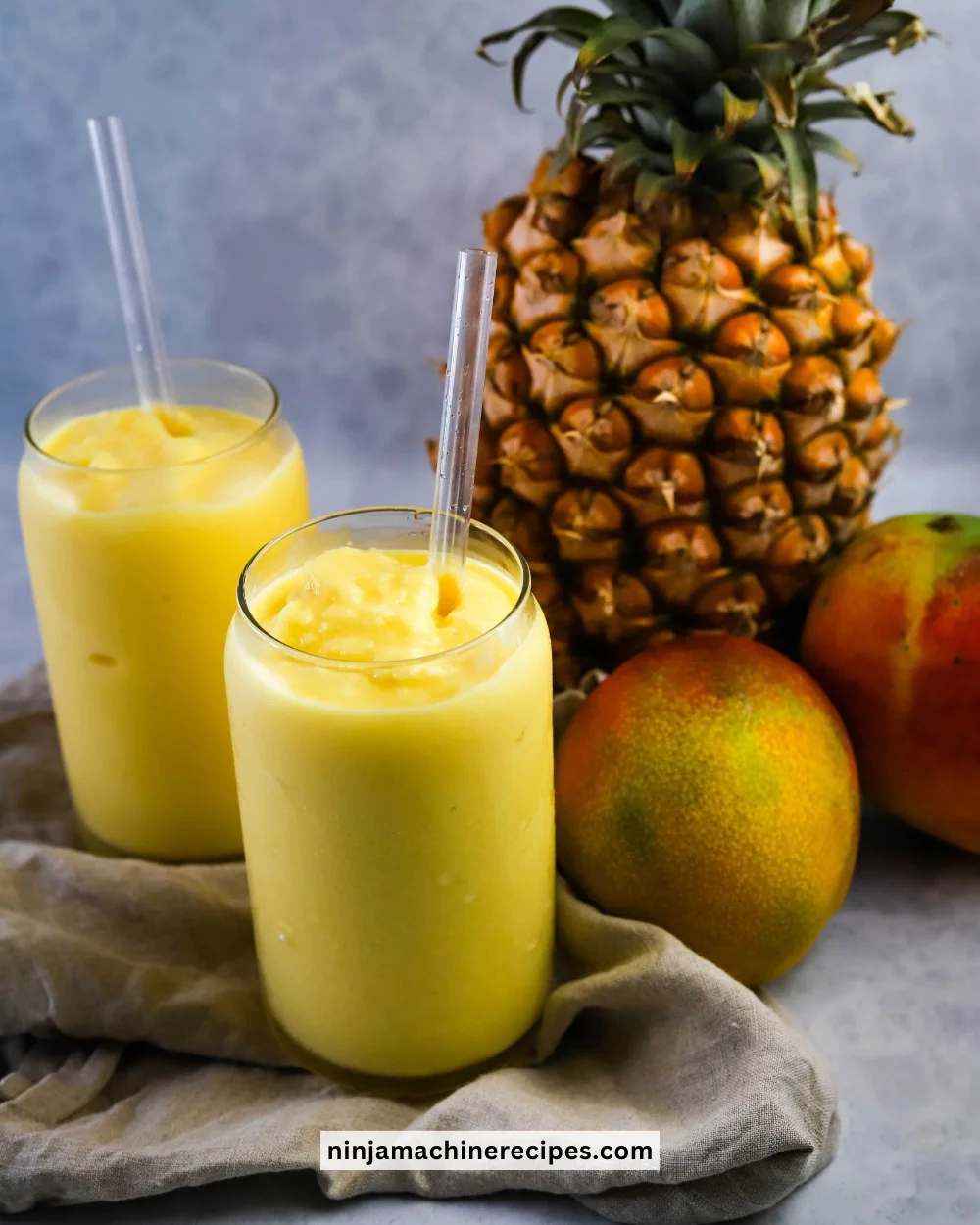 Mango Pineapple Slushie served in a glass with tropical fruits.