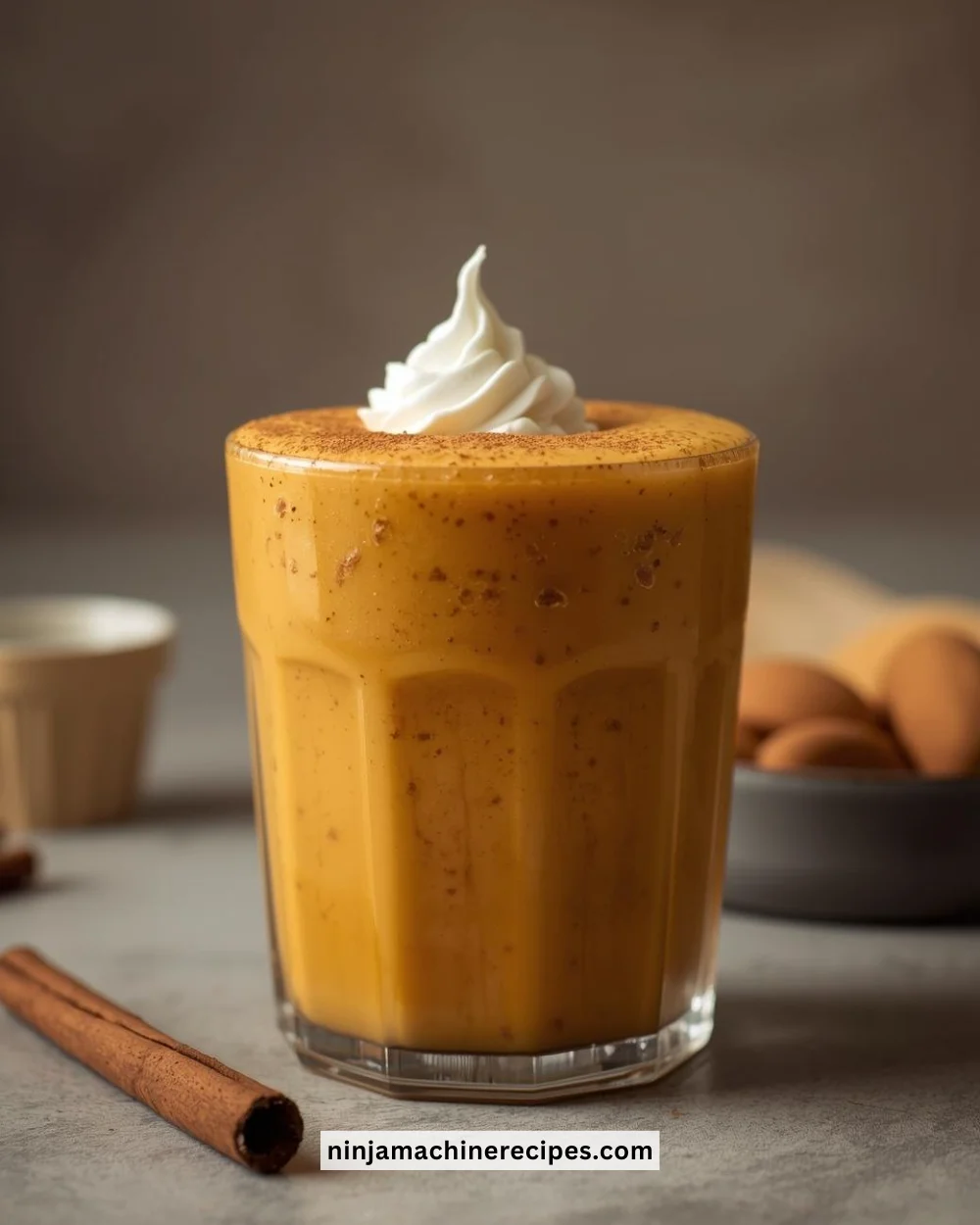 Pumpkin pie smoothie topped with whipped cream and spices in a glass