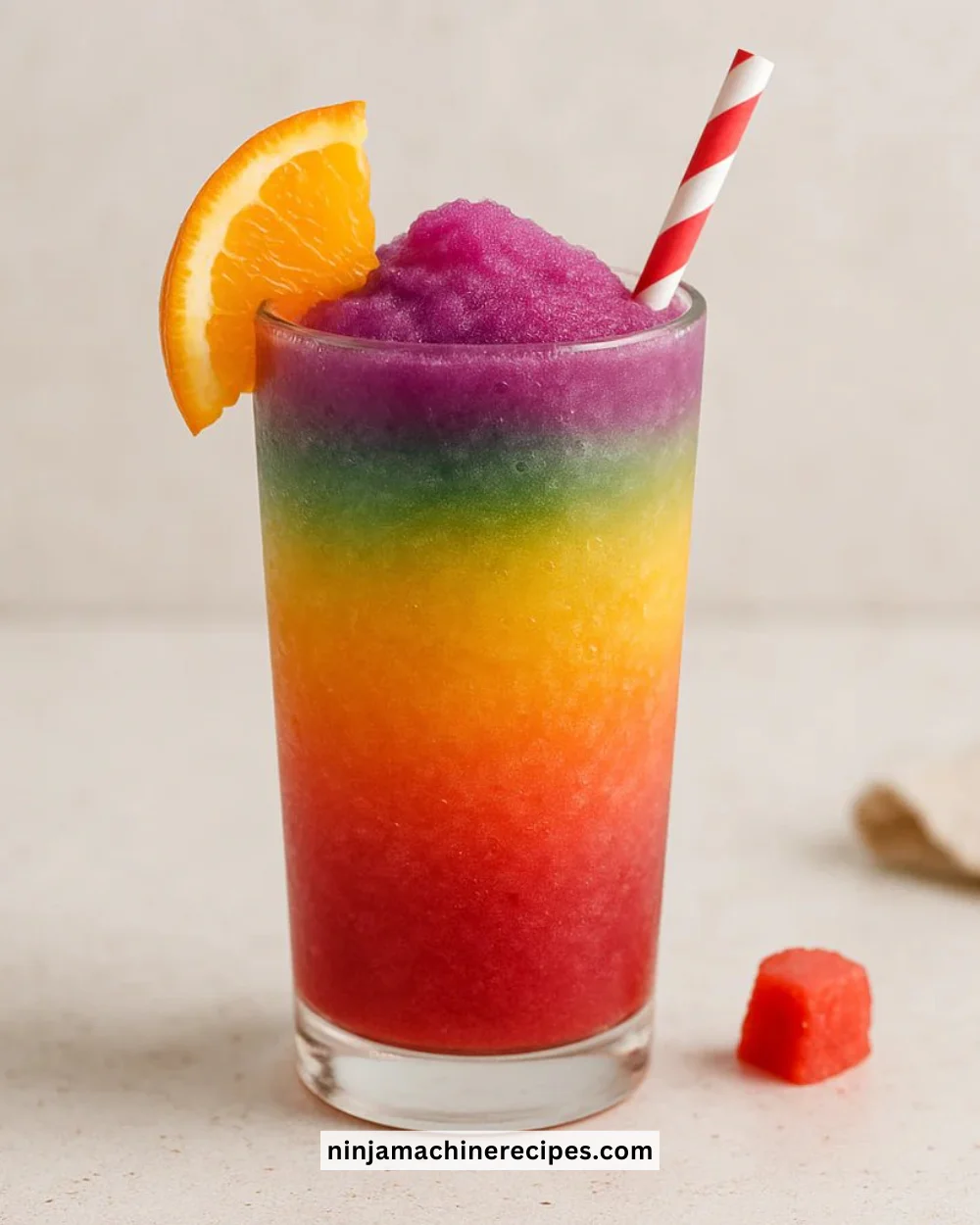 A vibrant Rainbow Slushie in a clear cup with colorful layers.