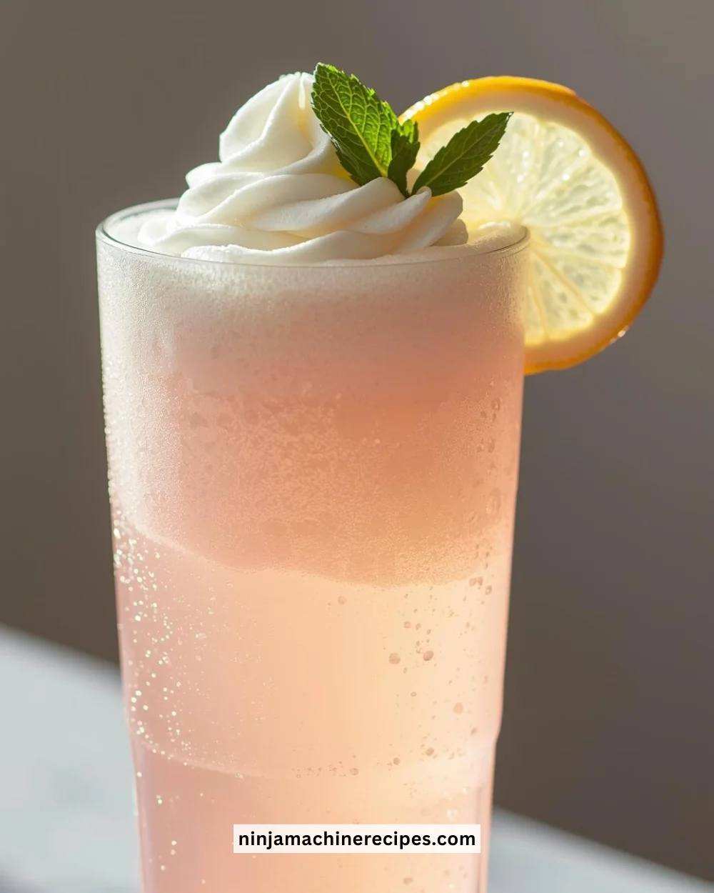 Delicious whipped pink lemonade in a glass with a lemon slice and mint