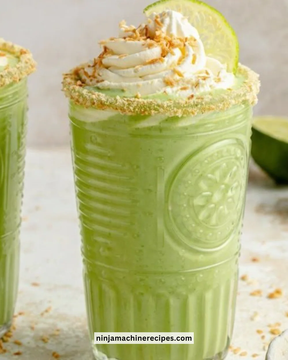 Creamy coconut key lime pie smoothie in a glass topped with lime slice and coconut flakes