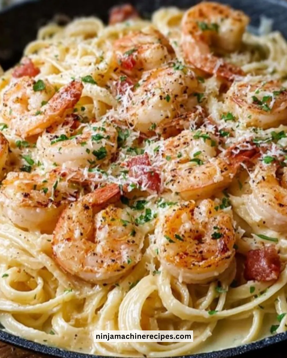 Plate of creamy garlic shrimp pasta topped with fresh parsley and grated cheese.