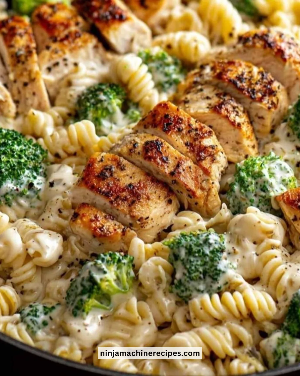 Creamy rotisserie chicken broccoli pasta in a bowl with a sprinkle of cheese.
