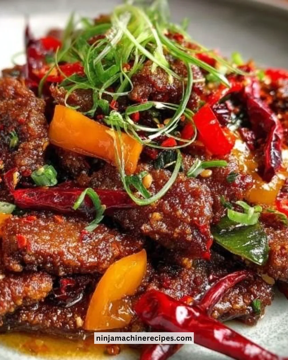 Plate of crispy chilli beef with colorful vegetables garnished with sesame seeds