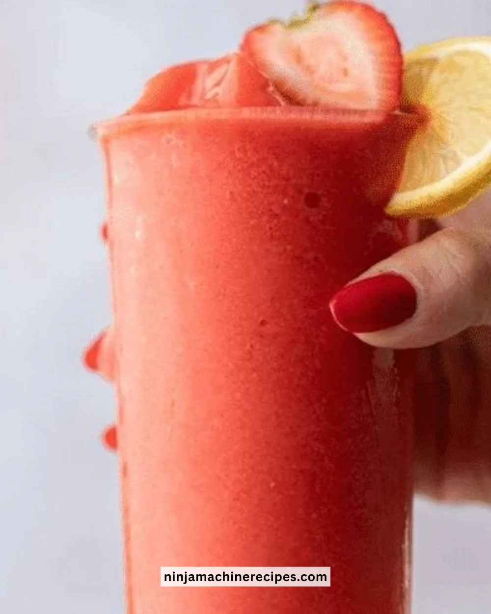Refreshing frozen strawberry lemonade in a glass with fresh strawberries.
