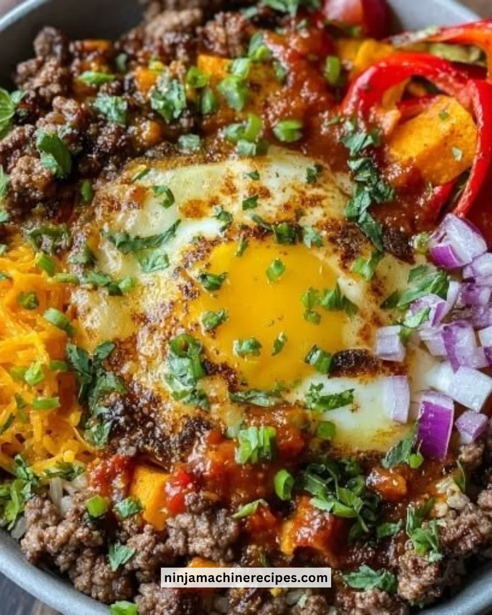 High protein ground beef power bowl topped with fresh vegetables and grains