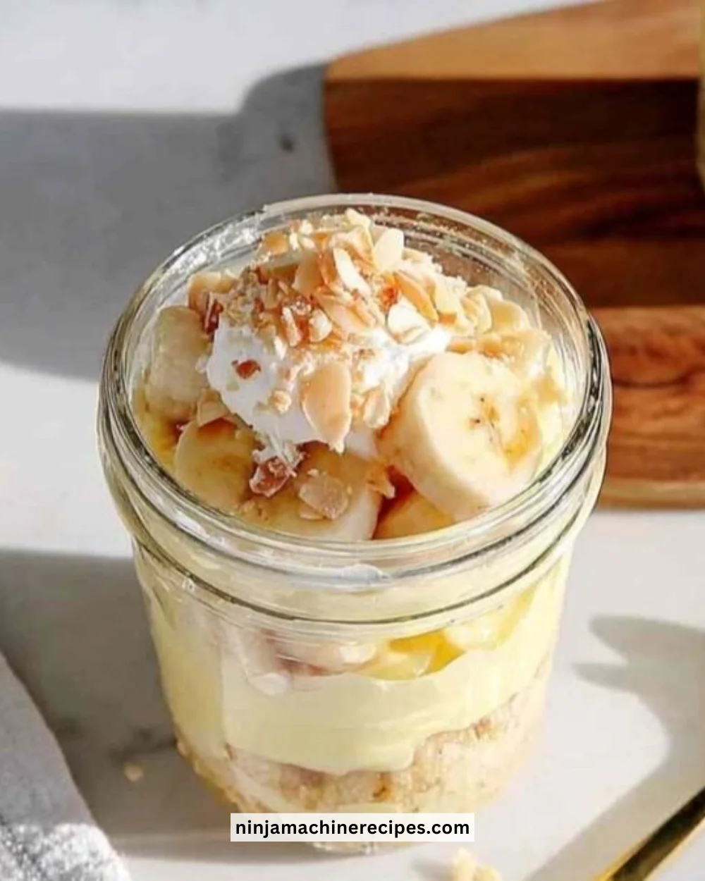 A bowl of creamy protein banana pudding topped with banana slices and whipped cream.
