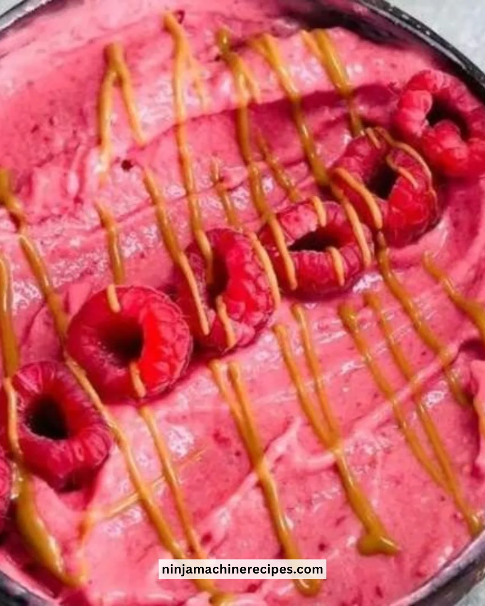 Thick raspberry smoothie bowl topped with fresh berries and granola.