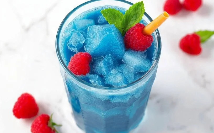 Delicious blue raspberry slushie in a clear cup with ice and a straw