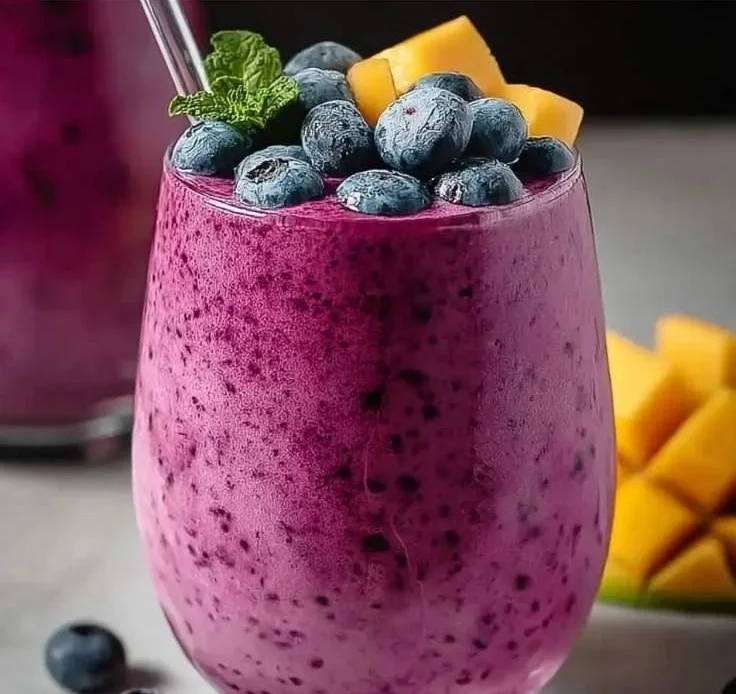 Delicious Blueberry Mango Smoothie in a glass with fresh fruits nearby