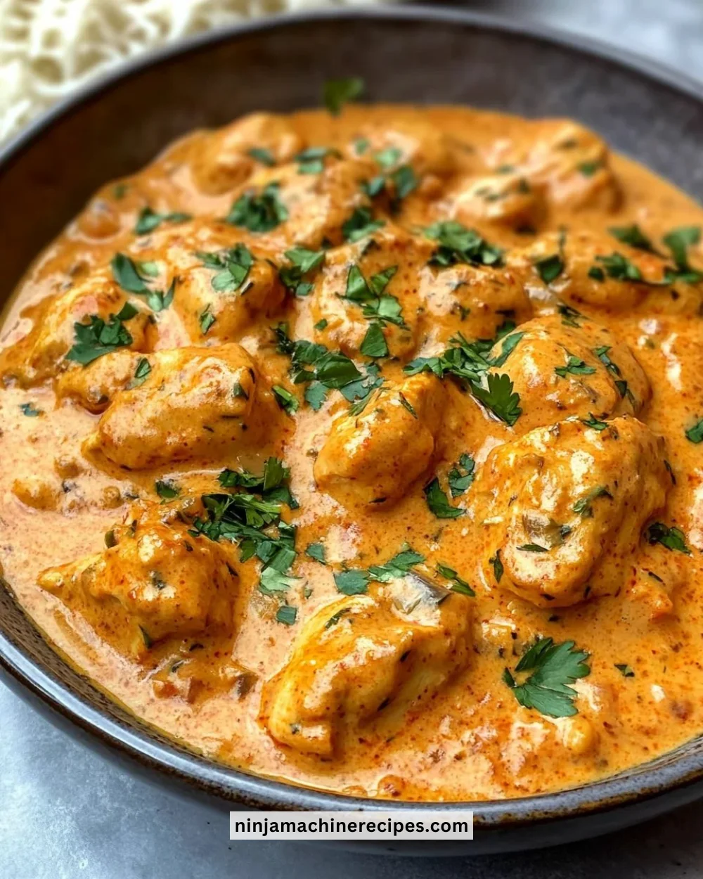 Plate of homemade butter chicken garnished with fresh herbs and served with naan