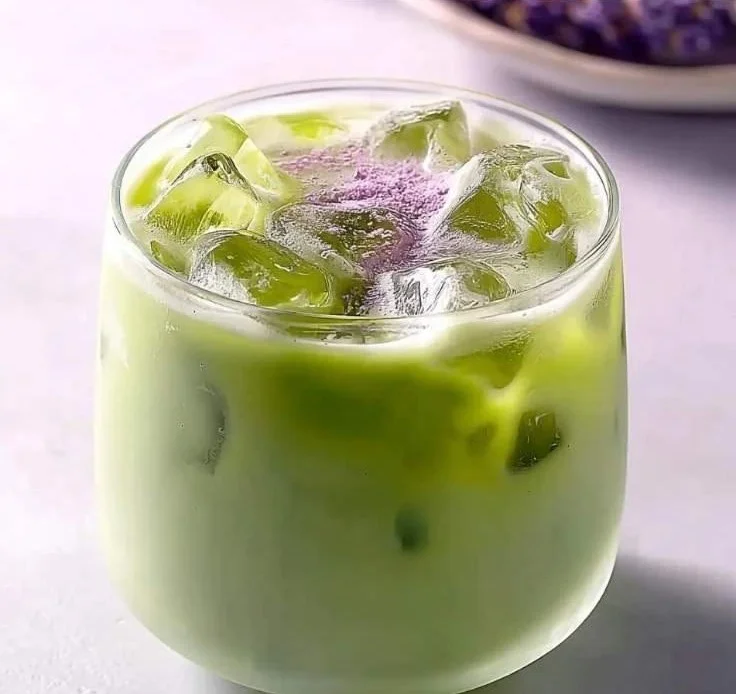 Iced Honey Lavender Matcha in a glass with lavender flowers and honey