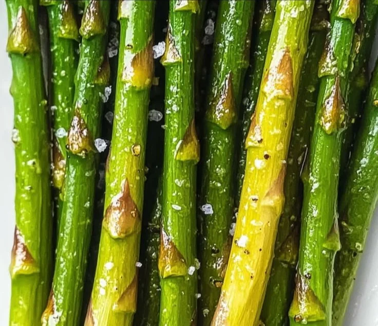 Plate of oven roasted asparagus garnished with spices and lemon.