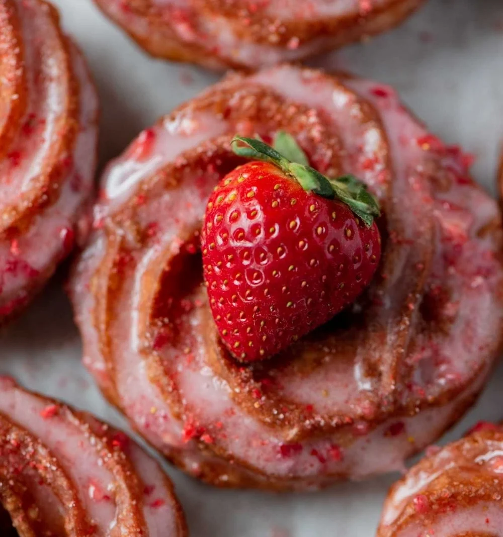 Strawberry glazed French crullers on a decorative plate