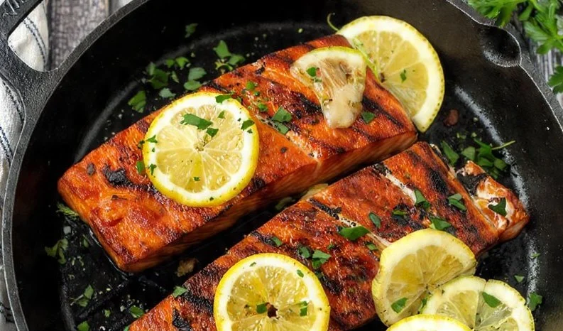 Woodfire grilled salmon served with lemon herb butter on a plate