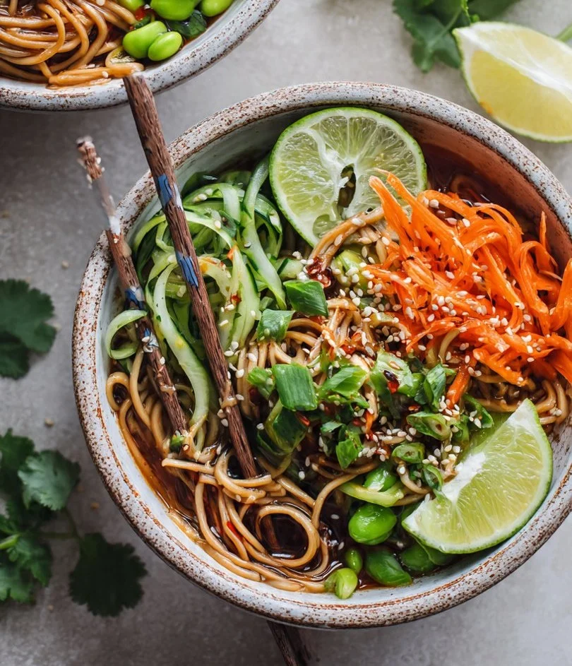 Delicious cold sesame noodle bowls garnished with vegetables and sesame seeds.