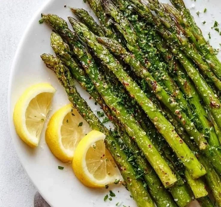 Plate of easy roasted asparagus with lemon served alongside a fresh salad.