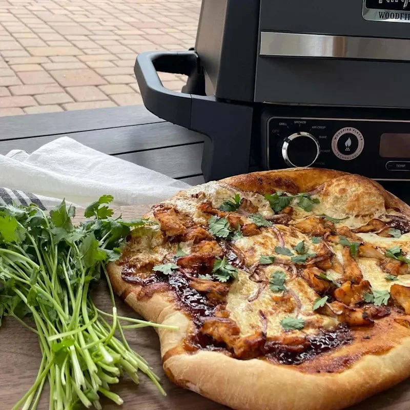 Grilled BBQ chicken pizza topped with cheese and fresh vegetables