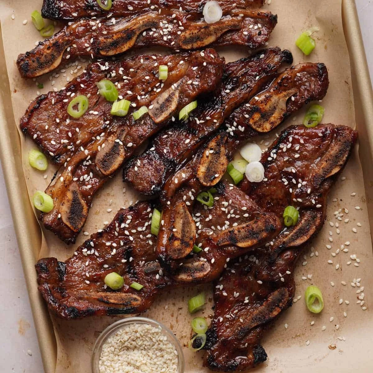 Juicy grilled beef ribs garnished with herbs and served on a cutting board.