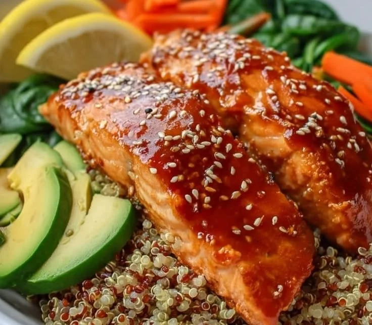Delicious hot honey salmon quinoa glow bowl topped with fresh vegetables.