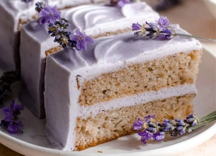 A slice of London Fog Tea Cake topped with creamy frosting and garnished with tea leaves.
