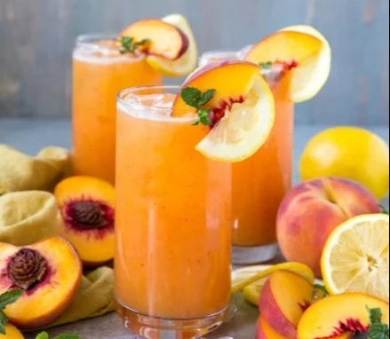 Refreshing glass of peach lemonade with fresh peaches and lemon slices