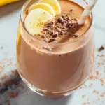 Delicious banana chocolate smoothie topped with chocolate shavings in a glass.