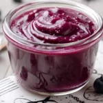 Delicious homemade blueberry curd in a glass jar with fresh blueberries