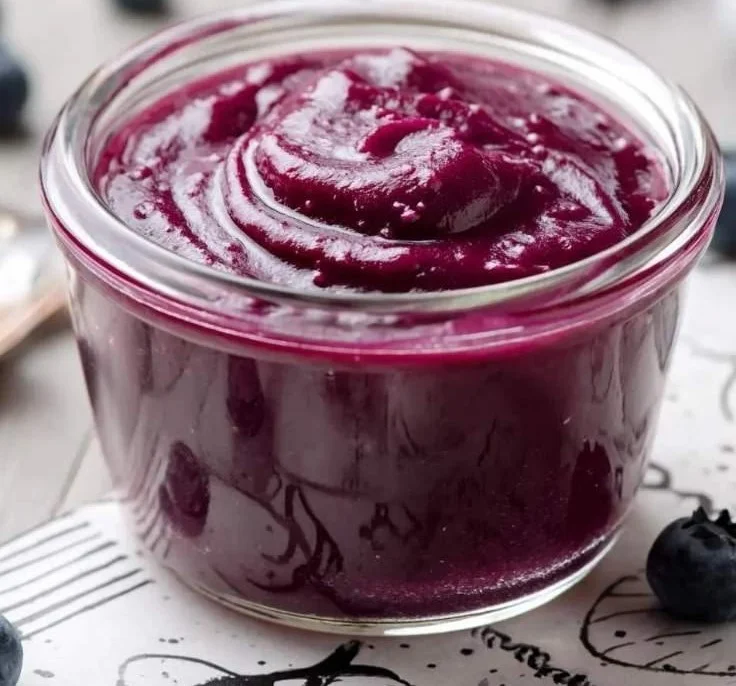 Delicious homemade blueberry curd in a glass jar with fresh blueberries