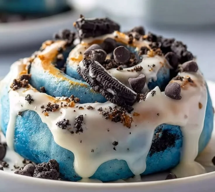 Delicious cinnamon rolls with blue icing and cookie crumbles on top.
