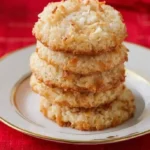 Delicious coconut cookies on a wooden plate with coconut flakes on top.