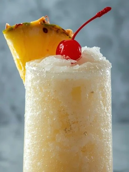 Creamy pineapple Pina Colada mocktail garnished with a cherry and pineapple slice