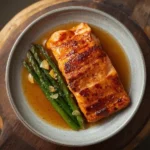 Oven-baked glazed salmon fillet garnished with herbs and lemon slices