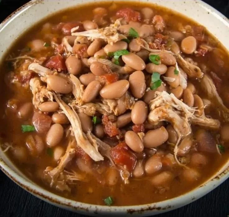 Bowl of spicy jalapeno beans and shredded chicken topped with fresh herbs