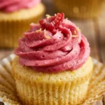 Lemon cupcakes topped with raspberry frosting in a decorated display.