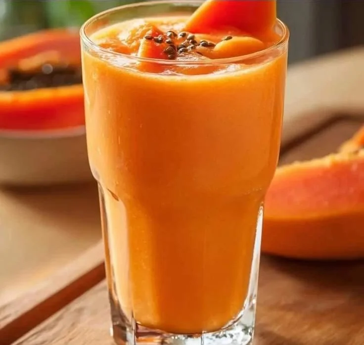 Delicious papaya smoothie in a glass with fresh fruit and a straw