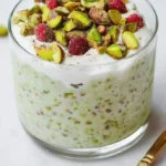 Bowl of pistachio overnight oats topped with nuts and fruit.