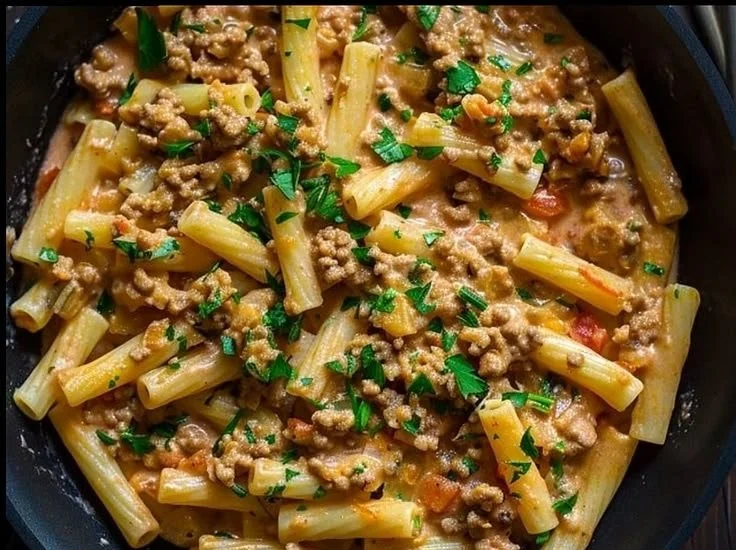 Creamy pasta dish with ground meat served in a bowl, garnished with herbs.